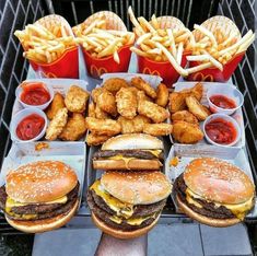 several hamburgers and fries are arranged on a grill