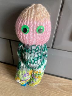 a knitted doll sitting on top of a wooden table next to a door handle