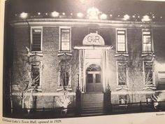 an old black and white photo of a building with lights on it's front entrance