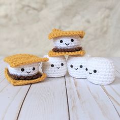 crocheted marshmallows with hats on them sitting on a wooden table