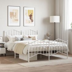 a white bed sitting on top of a wooden floor next to a lamp and window