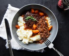 a bowl filled with meat and mashed potatoes next to a bottle of booze