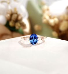 a blue stone ring sitting on top of a white table next to flowers and other decorations