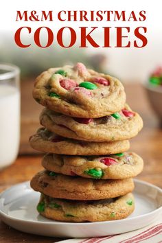 a stack of m & m christmas cookies on a plate with milk in the background