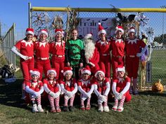 a group of people dressed up as santa clause posing for a photo in front of a fence