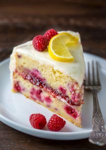 a piece of cake on a plate with raspberries and lemon