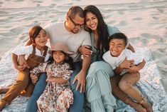 a family sitting on the beach with their arms around each other and smiling at the camera