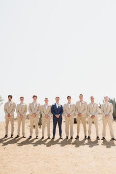 a group of men standing next to each other in front of a desert area with cacti