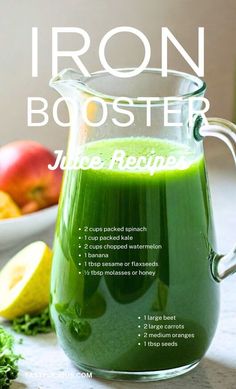 a green liquid in a glass pitcher next to some fruit