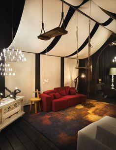 a living room with a red couch and chandelier hanging from it's ceiling