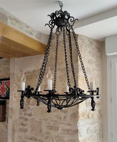 a chandelier with candles hanging from it's arms in front of a stone wall