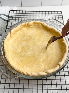 a person is cutting into a pie with a knife on the wire rack next to it