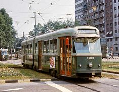 an old green trolley car is on the street