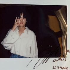 an old photo of a woman holding her hand up to her face and making a peace sign