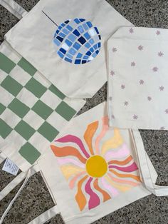 three bags with designs on them sitting on the ground next to each other and one bag has a flower in it