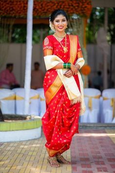 a woman in a red and gold sari standing on a brick walkway with white tables