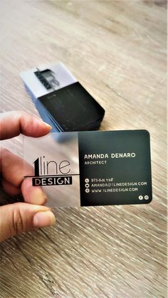 a person holding up a business card on top of a wooden table