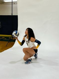 a woman kneeling down holding a volleyball ball