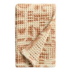 an orange and white blanket folded on top of each other with a brown checkered design