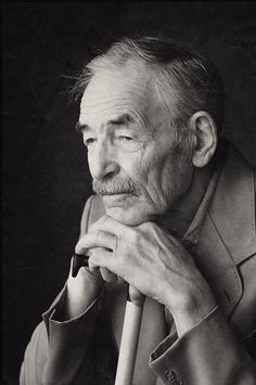 black and white photograph of an older man leaning on a chair with his hand under his chin