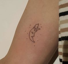 a woman's arm with a small tattoo of a cat on it, and the moon behind her