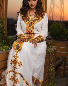 This stunning Habesha dress is made of Menen fabric, a traditional Ethiopian fabric known for its durability and intricate patterns. The upper part of the dress is made of handwoven shimena fabric, which adds a unique texture and elevates the overall design. The tilf embroidery, a type of delicate chain stitch embroidery, is carefully crafted around the neckline, sleeves, and bottom hemline of the dress, adding a touch of elegance and sophistication. The dress is tailored to fit comfortably and Transitional White Kaftan, White Long Sleeve Transitional Kaftan, White Long Sleeve Dress With Traditional Patterns, Long Sleeve Dress With Multicolor Traditional Embroidery, Transitional Long Sleeve Maxi Dress, Bohemian Long Sleeve Maxi Dress For Transitional Season, Bohemian Long Sleeve Habesha Kemis For Festive Occasions, Bohemian White Long Sleeve Habesha Kemis, White Bohemian Long Sleeve Habesha Kemis