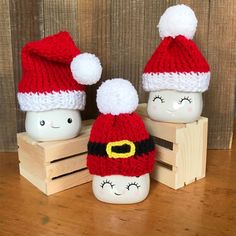 three knitted santa hats sitting next to each other on a wooden crate with wood planks