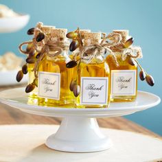 three bottles of honey sitting on top of a white cake plate next to other food items