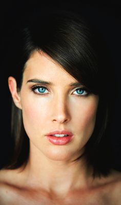 a beautiful young woman with blue eyes posing for a photo in front of a black background