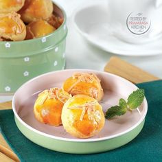 three small pastries on a plate next to a potted plant and spoons