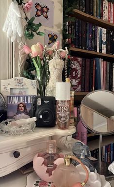 there are many items on the table in front of the bookshelf and mirror