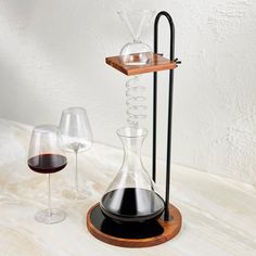 two wine glasses and a decanter are sitting on a table with a wooden tray