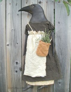 a black bird wearing an apron and holding a potted plant in it's pocket