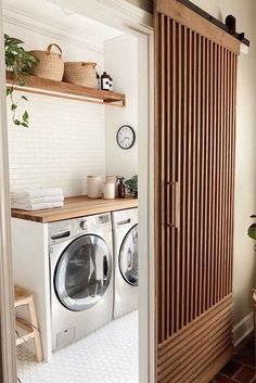 a washer and dryer in a small room with wooden shelves on the wall