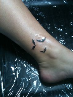 a person's foot with a small bird tattoo on the left side of their leg