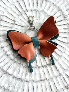 a brown and green leather bow keychain sitting on top of a white plate