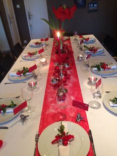 the table is set with plates, silverware and red napkins for christmas dinner