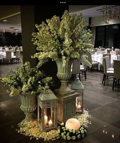 an arrangement of flowers and candles in vases on the floor at a wedding reception