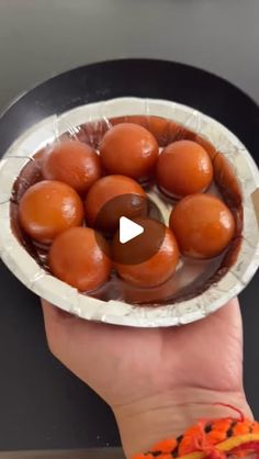 a person holding a paper plate filled with brown eggs on top of a black counter