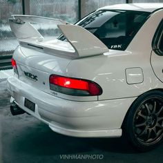 the back end of a white car parked in a garage