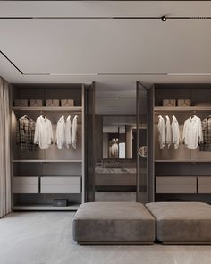 a large walk in closet with clothes on hangers and a foot stool next to it