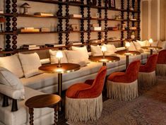 a room filled with lots of white couches and chairs next to wooden shelving