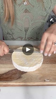 a woman is using a knife to cut up something on a wooden board with white paint