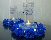 blue roses and candles are arranged in a vase