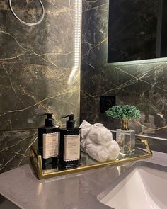 a bathroom sink with soap and lotion bottles on it next to a large mirror