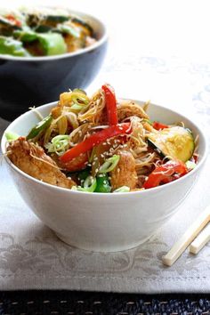 a white bowl filled with food next to chopsticks