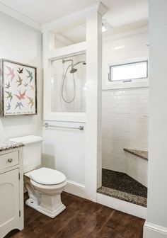 a bathroom with white fixtures and wood floors