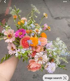 a person holding a bouquet of flowers in their hand on the street with an image search button below