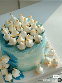 a blue cake with white frosting and yellow ducks on top is sitting on a plate