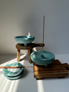 three bowls and two chopsticks sitting on a wooden stand in front of a white wall